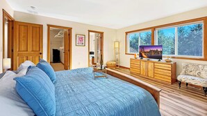 Un dormitorio con una cama grande, un armario de madera, cómoda y televisor sobre un mueble de madera.