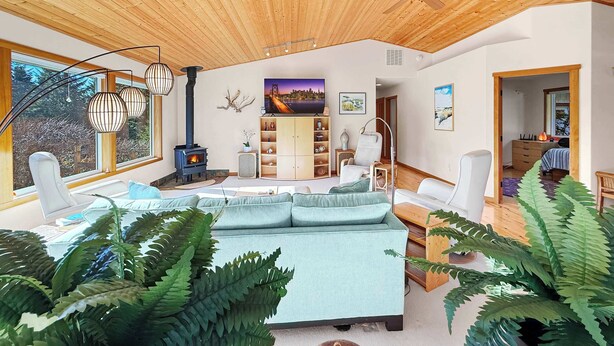 Amplia sala de estar con un sofá grande, techo de madera, chimenea y ventanas amplias.