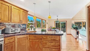 Una cocina amplia con armarios de madera, una isla grande e iluminación colgante.