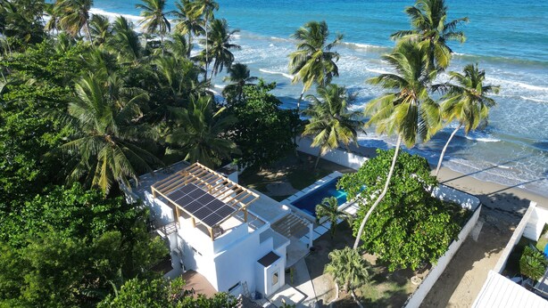 Una propiedad costera con un edificio blanco, piscina y palmeras.