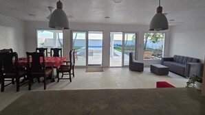 Amplia habitación con comedor, sofá y un amplio ventanal corredera que da a un patio.