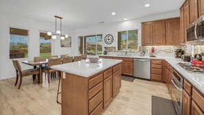 Une cuisine moderne avec des meubles en bois, un grand îlot central et un coin repas avec des chaises.