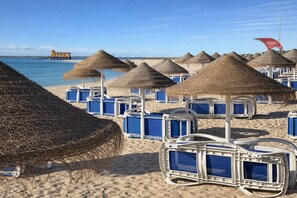 Una platja amb sombrerets de palla i gandules blaves.