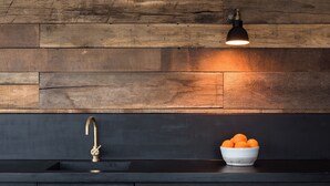 A kitchen with a dark countertop, a gold faucet, and a bowl of oranges. - Panoramic sea views, private terrace, parking, jacuzzi, pool, gym (Falmouth)