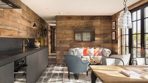 A modern kitchen with a built-in oven, a wooden wall, and a dining area with a table and chairs. - Panoramic sea views, private terrace, parking, jacuzzi, pool, gym (Falmouth)