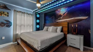 A bedroom with a bed, a nightstand, a ceiling fan, and a wall mural. - FREE Bbq+Pool Heat-8bdrm Windsor Island-Theatre/Arcade (Davenport)