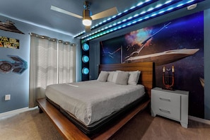 A bedroom with a bed, a nightstand, a ceiling fan, and a wall mural. - FREE Bbq+Pool Heat-8bdrm Windsor Island-Theatre/Arcade (Davenport)