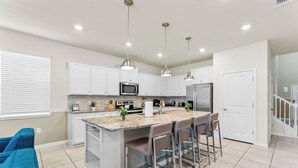 A modern kitchen with white cabinets, a granite countertop, stainless steel appliances, and pendant lighting. - FREE Bbq+Pool Heat-8bdrm Windsor Island-Theatre/Arcade (Davenport)