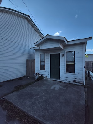 A small, single-story house with a front door, two windows, and a garage door.