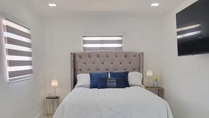 Una camera da letto moderna con un letto grande, una televisione a schermo piatto e un pavimento in marmo.