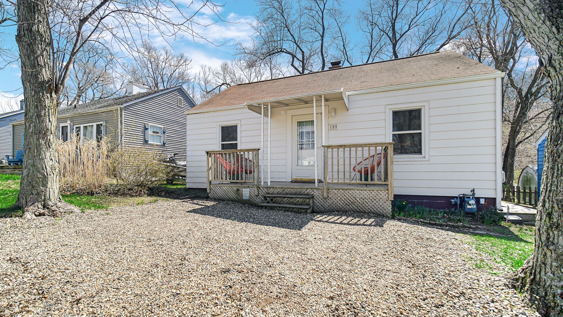 A single-story house with a front porch, a gravel driveway, and a small front yard.