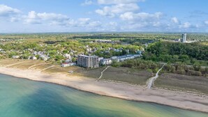 Vue aérienne d  ’une zone côtière comprenant une plage, un ensemble de logements et une tour située au loin.