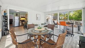 Une cuisine moderne équipée d’un réfrigérateur, d’une cuisinière et d’un coin repas avec des chaises en osier et une table en verre.