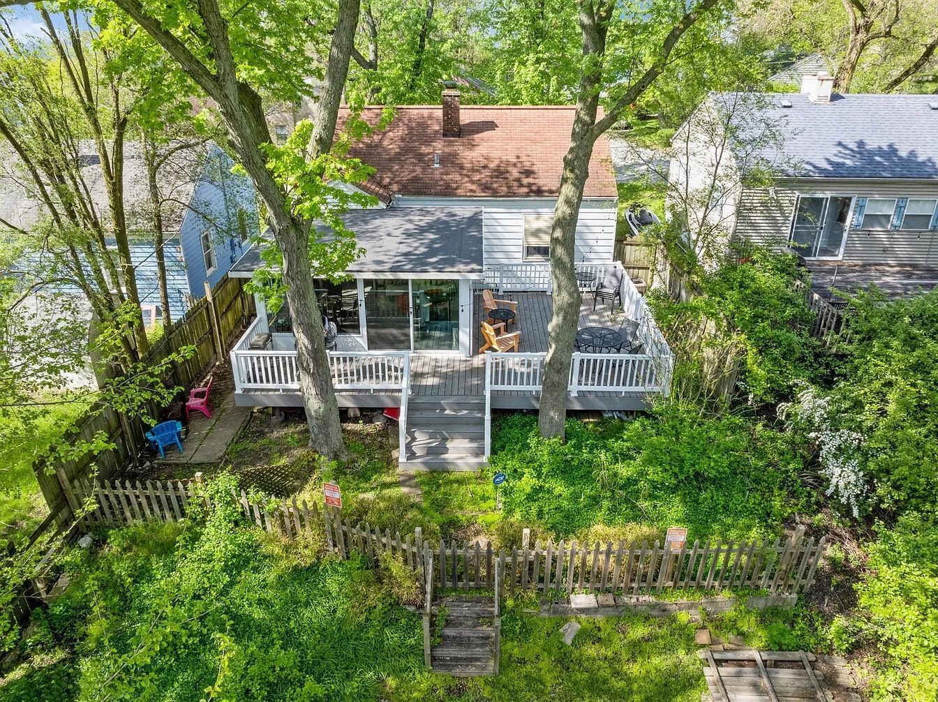 Une maison avec un porche couvert, une cour clôturée et une petite terrasse.