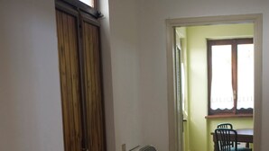 A hallway with a wooden cabinet, a radiator, and a dining area with chairs and a table.