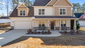 A two-story house with a front porch, a garage, and a well-maintained lawn. - Privacy in the Pines + Hot Tub +Custom Fire Pit (Aberdeen)