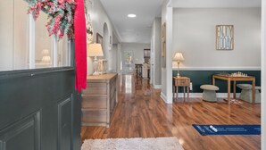 A hallway with wooden flooring, a red decorative hanging, and a chess table. - Privacy in the Pines + Hot Tub +Custom Fire Pit (Aberdeen)