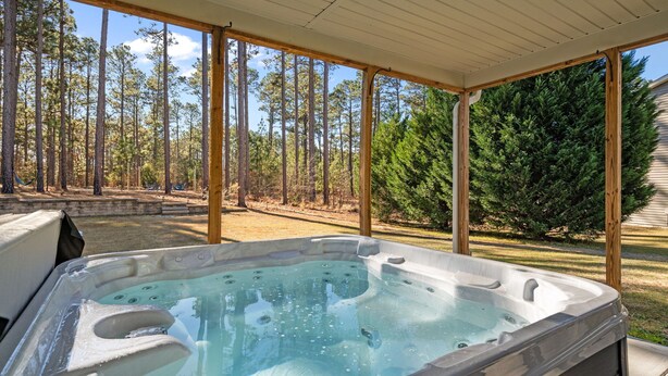 A hot tub in an outdoor covered area with a view of a forest. - Privacy in the Pines + Hot Tub +Custom Fire Pit (Aberdeen)