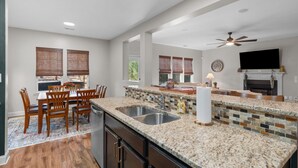 A spacious kitchen with granite countertops, a built-in sink, and a dining area with wooden chairs. - Privacy in the Pines + Hot Tub +Custom Fire Pit (Aberdeen)