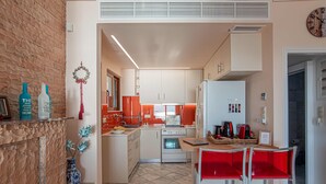 A compact kitchen with white cabinets, a built-in oven, and a coffee machine. - Feliz Apt- Breathtaking Seaview and Sunset by ΜΡS (Anavissos)