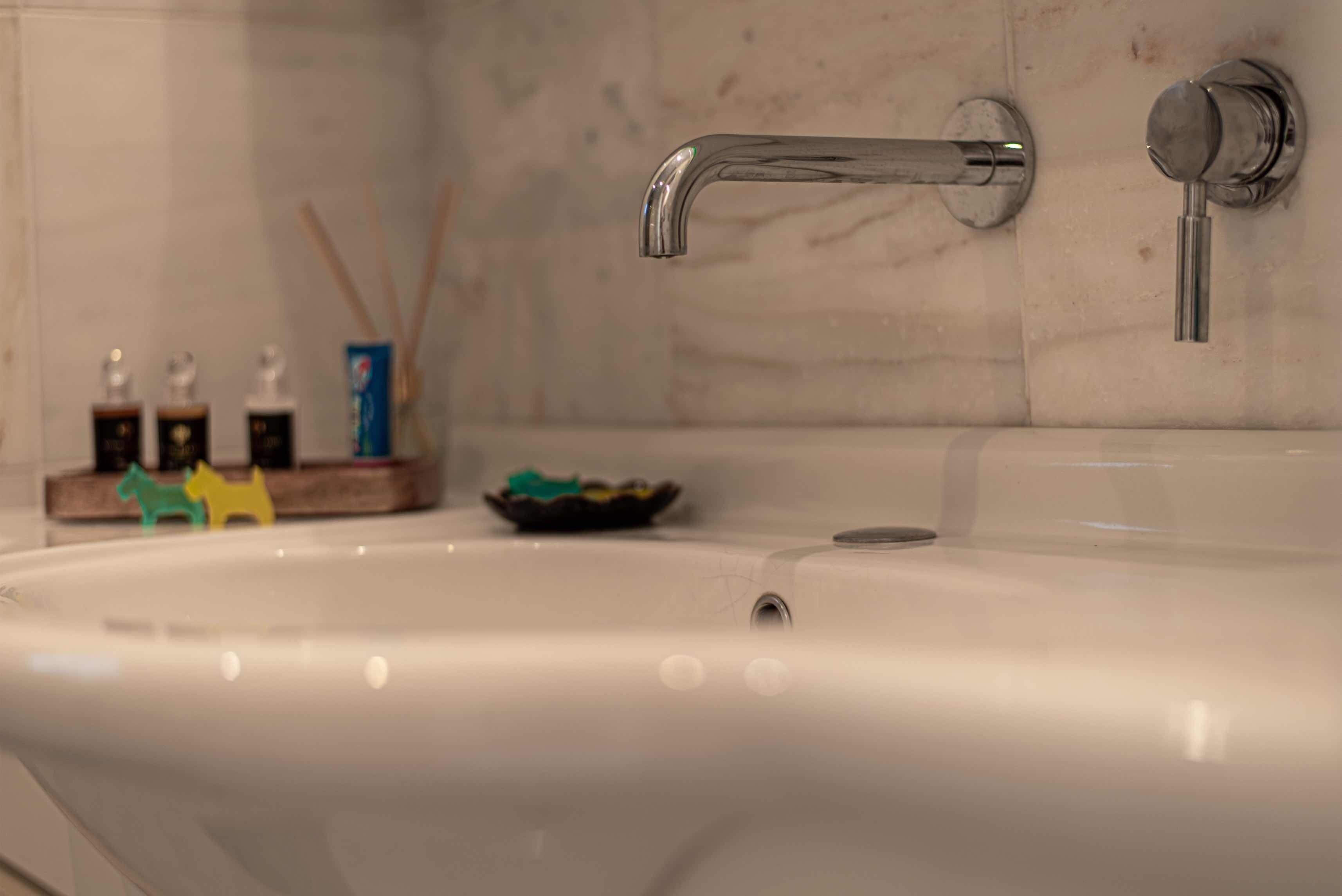 A bathroom sink with a chrome faucet and a small bowl of toiletries on the counter.