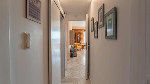 A hallway with a framed inspirational quote, a light switch, and framed pictures on the wall. - Feliz Apt- Breathtaking Seaview and Sunset by ΜΡS (Anavissos)