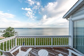 A wooden deck with white railings, a round table, and a bench.