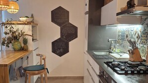 Ett kök med en köksö i trä, en gasspis, en diskho och dekorativa, hexagonformade väggdekorationer.