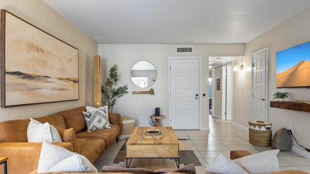 A modern living room with a brown leather sofa, a wooden coffee table, and a large painting on the wall.