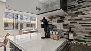 A modern kitchen with a large island, a coffee machine, and a dish soap bottle.