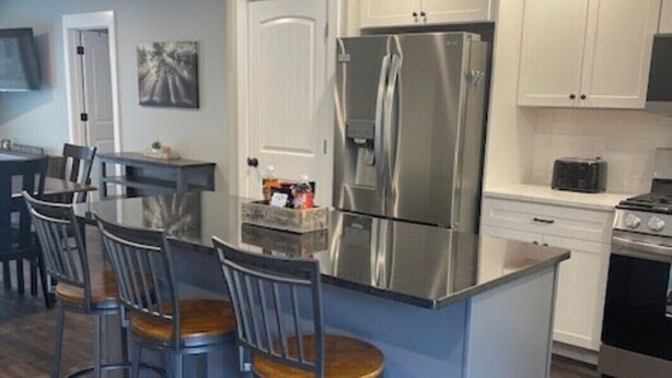 Una cucina moderna con isola centrale, elettrodomestici in acciaio inossidabile e sgabelli da bar.
