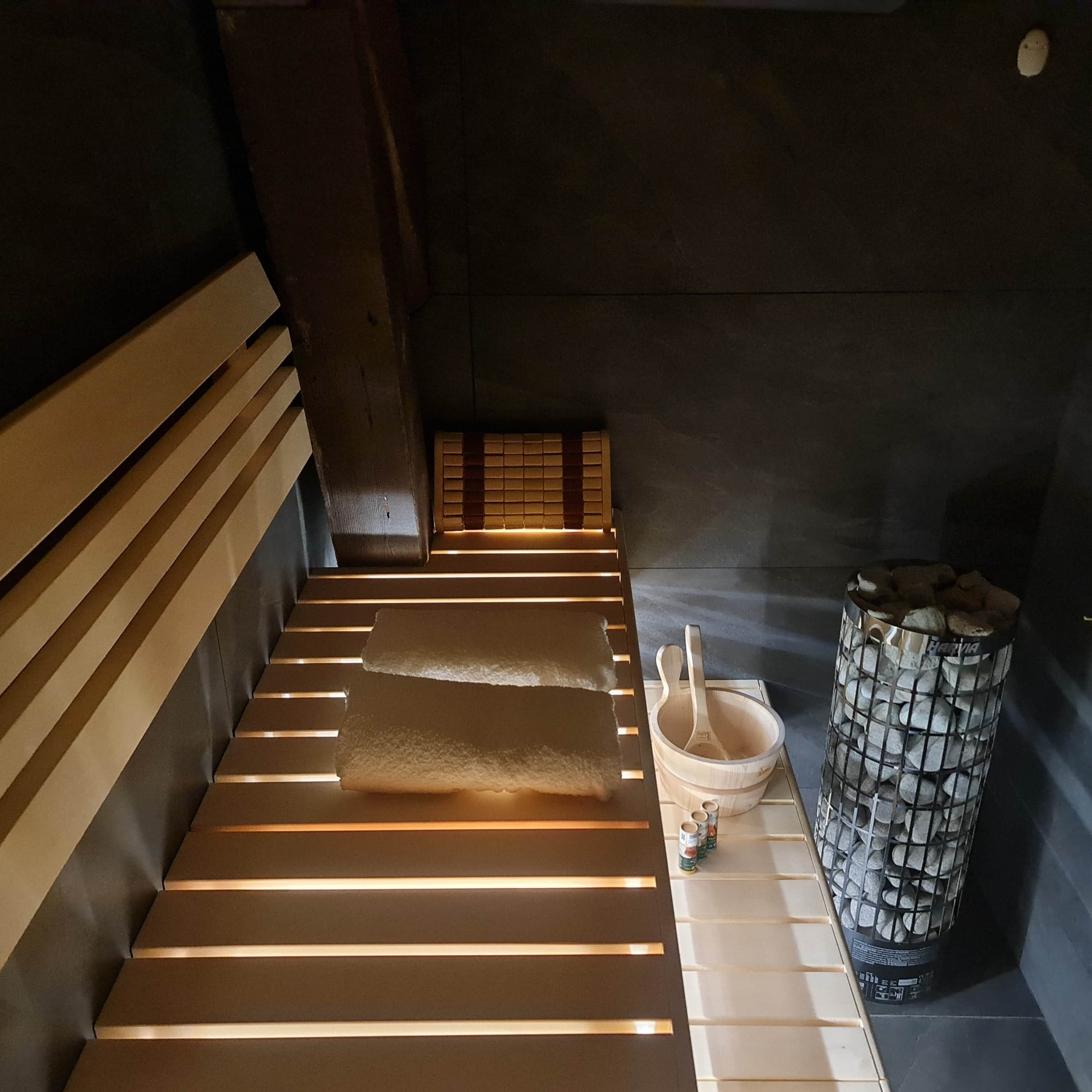 Un sauna avec des bancs en bois, un seau en bois et un récipient rempli de pierres.
