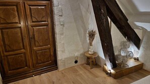 Una habitación con puerta de madera, una mesita con un florero y una escultura metálica decorativa.