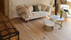 Una sala de estar acogedora con un sofá, dos mesas redondas de centro y un elemento decorativo en la pared.