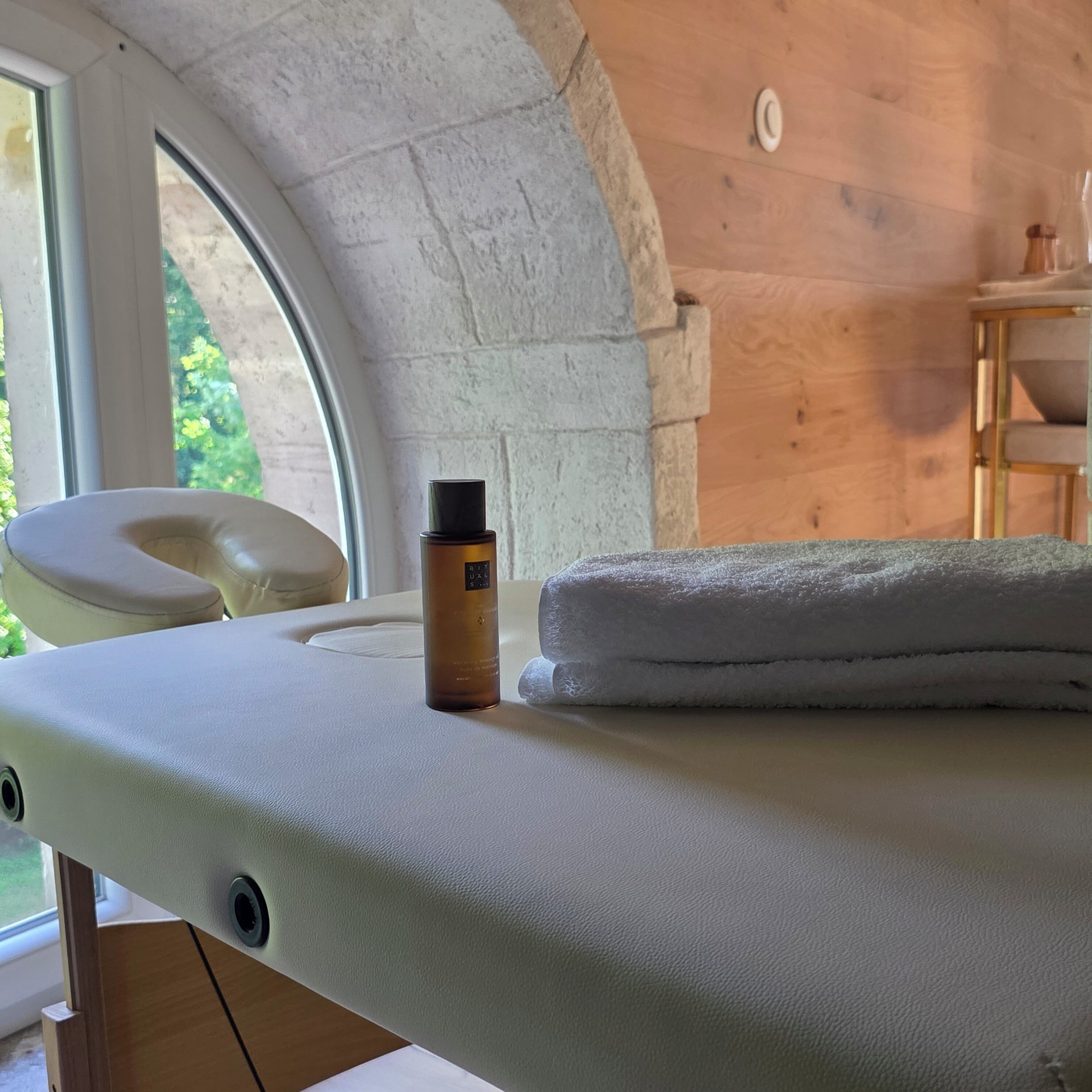 Ein Massagestuhl mit Lotionflasche, Handtuch und einem Fenster mit Blick auf Grünflächen.