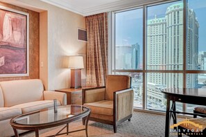 Ein Hotelzimmer mit großem Fenster, einer Couch, einem Sessel, einer Lampe und einem Gemälde an der Wand.