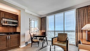 Une chambre d’hôtel moderne dotée d’une cuisine, d’un coin repas et d’une grande fenêtre offrant une vue sur la ville.