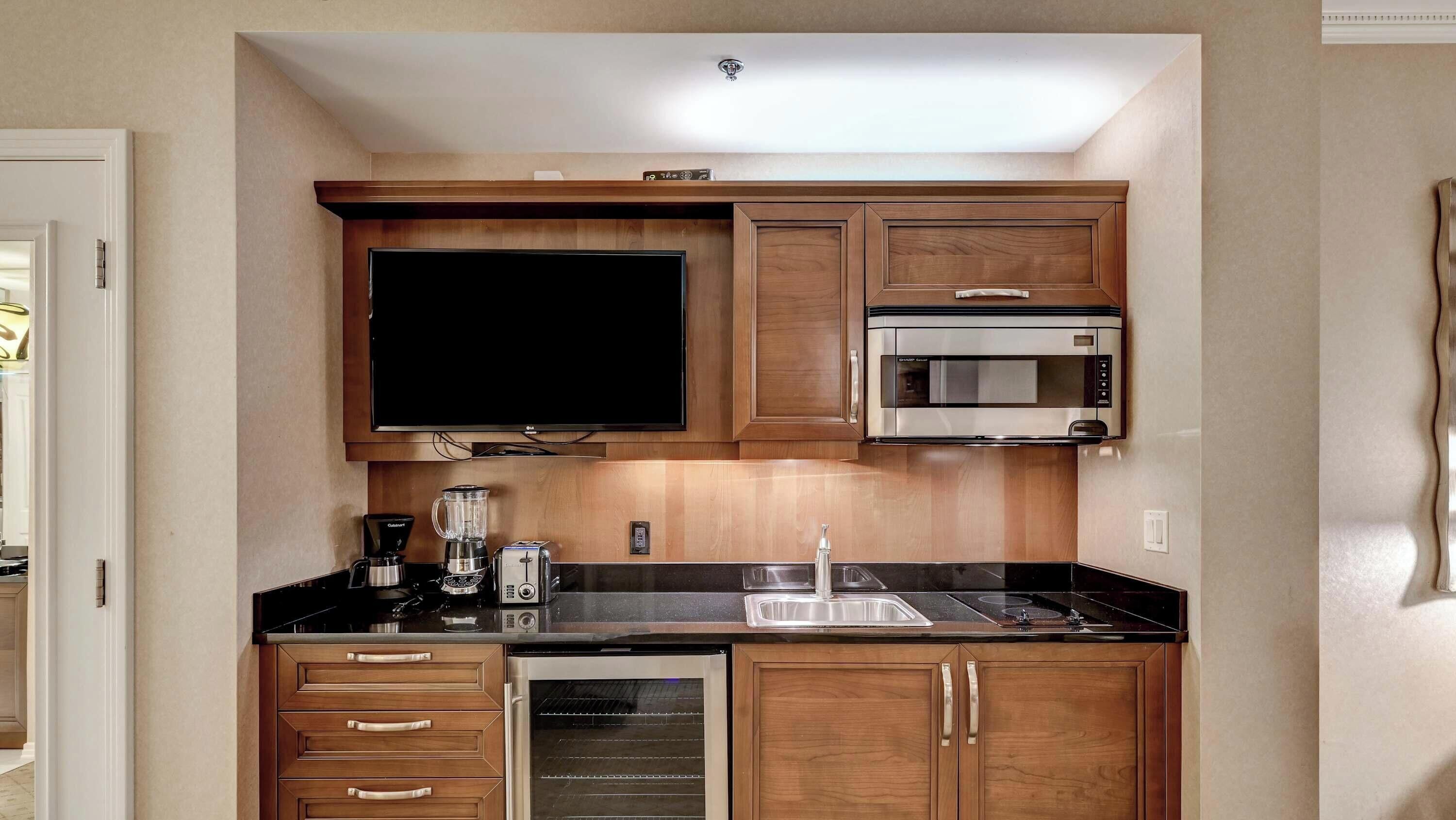 A compact kitchen with a flat-screen TV, a microwave, a toaster, and a dishwasher.