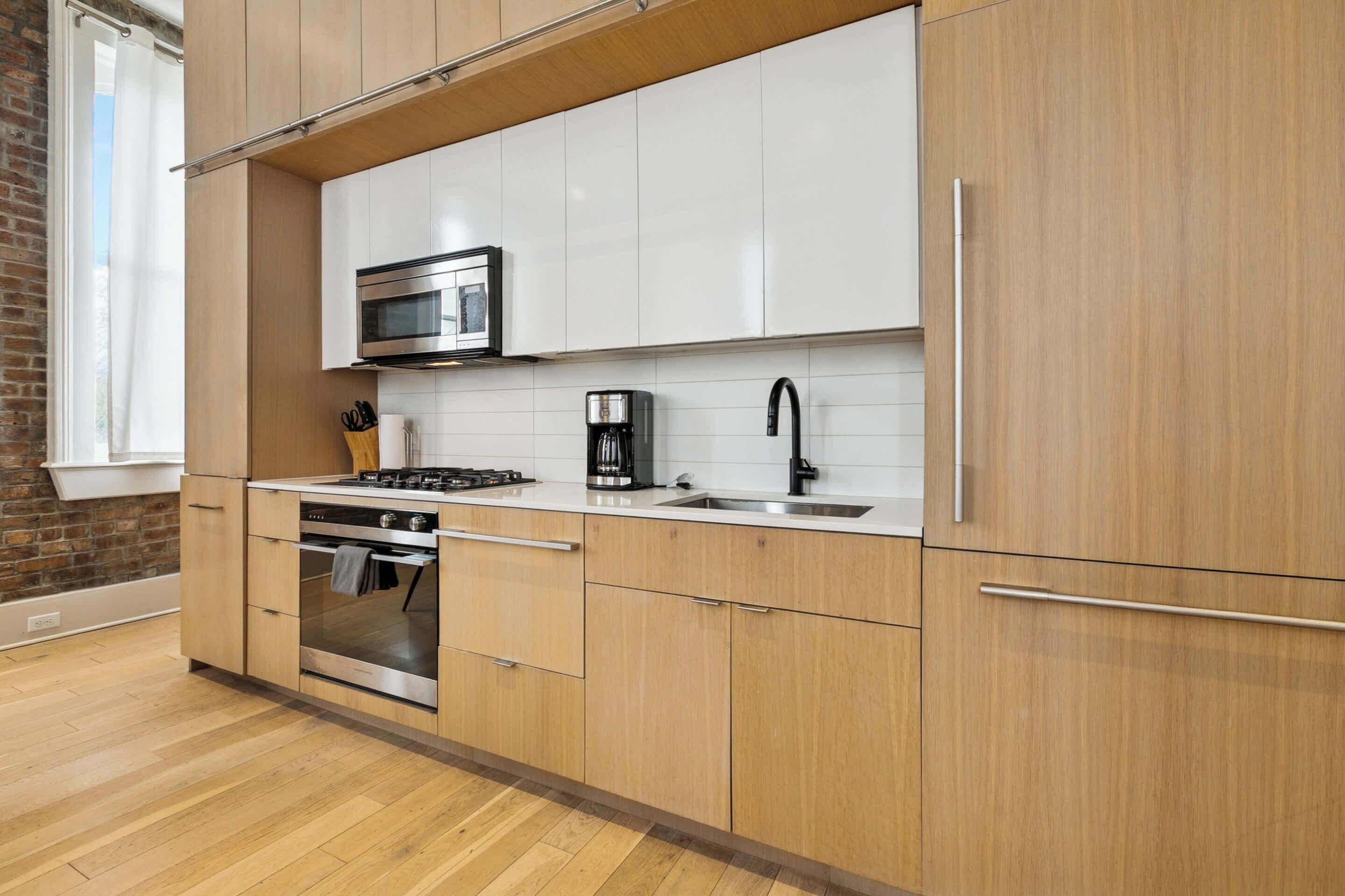 Una cucina moderna con mobili in legno, un forno in acciaio inossidabile, un microonde e una macchina per il caffè.