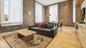 Ein modernes Wohnzimmer mit Backsteinwand, einer Couch, einem Couchtisch und einem Teppich.