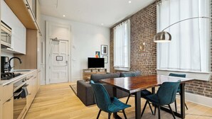 Eine moderne Küche mit Einbauofen und einem Essbereich mit Holztisch und Türkis-Stühlen.