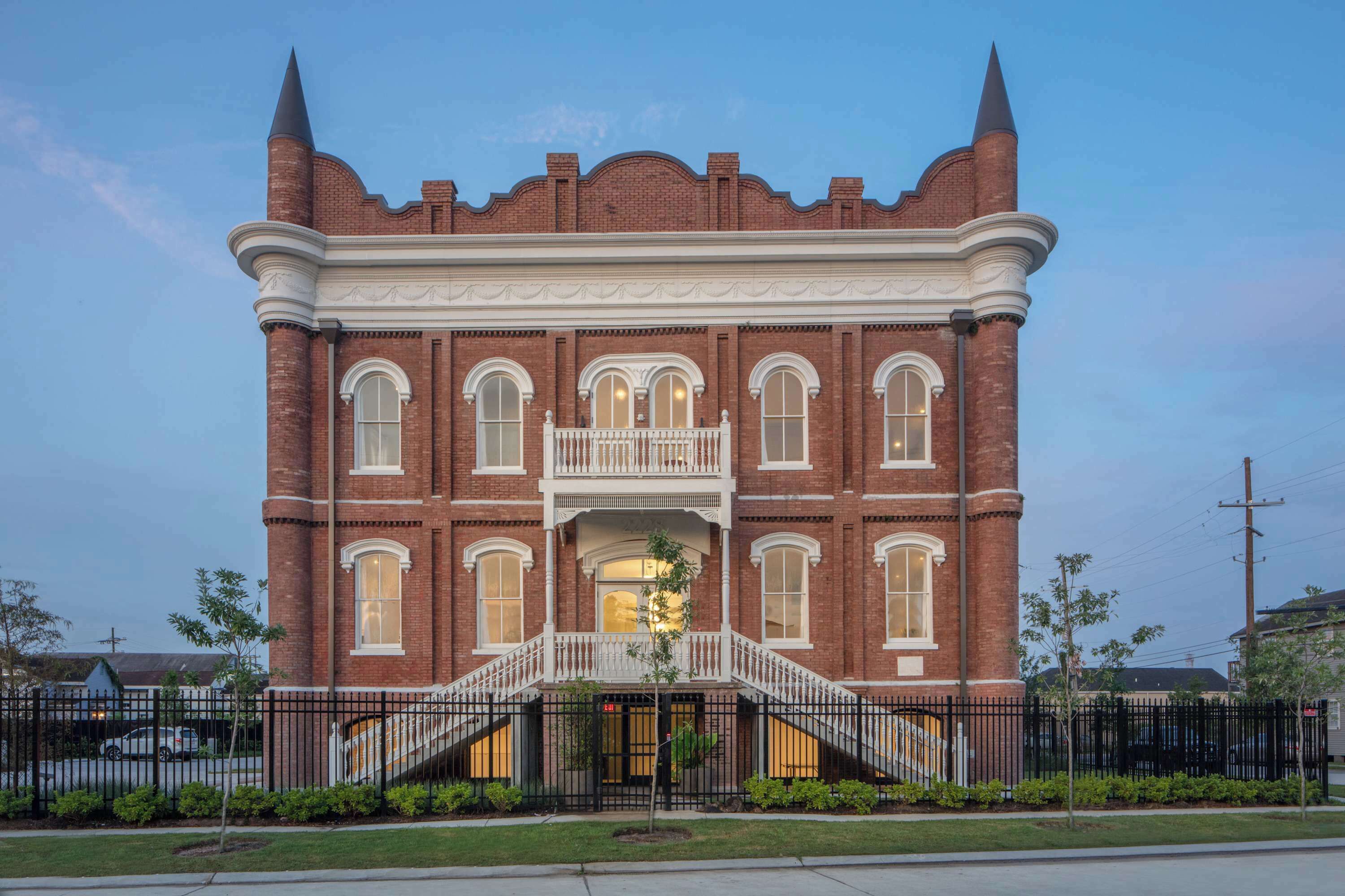 A large brick building with a central entrance, a balcony, and a symmetrical facade.