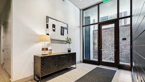 A modern lobby with a wooden console, a floor lamp, and a potted plant. - Walkable 3BR Apartment w/ Balcony | Near Bourbon St + Superdome (New Orleans)