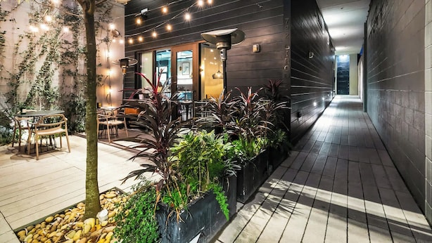 An indoor courtyard with a dining area, potted plants, and string lights. - Walkable 3BR Apartment w/ Balcony | Near Bourbon St + Superdome (New Orleans)