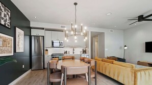 A modern kitchen with a central island, stainless steel appliances, and a dining area with a table and chairs. - Walkable 3BR Apartment w/ Balcony | Near Bourbon St + Superdome (New Orleans)