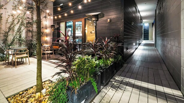 An indoor courtyard with a dining area, potted plants, and string lights. - Sleek 2 BR Apartment | Near Bourbon St. + Superdome (New Orleans)