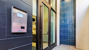 En moderne elevator med kontrolpanel, glasdøre og flisegulv.