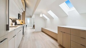 A modern kitchen with a skylight, wooden flooring, and built-in cabinets. - Modern 2BR in Historic Schoolhouse | Gated Parking | Near Superdome (New Orleans)
