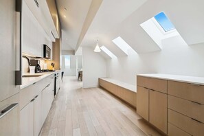 A modern kitchen with a skylight, wooden flooring, and built-in cabinets. - Modern 2BR in Historic Schoolhouse | Gated Parking | Near Superdome (New Orleans)