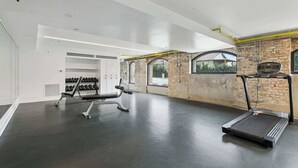 Ein modernes Fitnessstudio mit Laufband, Gewichtbank und Kurzhanteln.